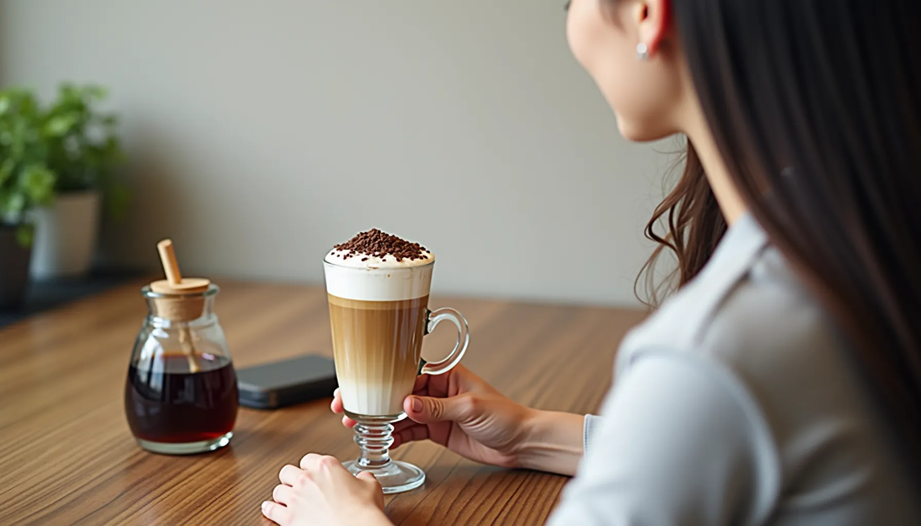 A person enjoying a beautifully layered fount coffee topped with chocolate sprinkles at a café.